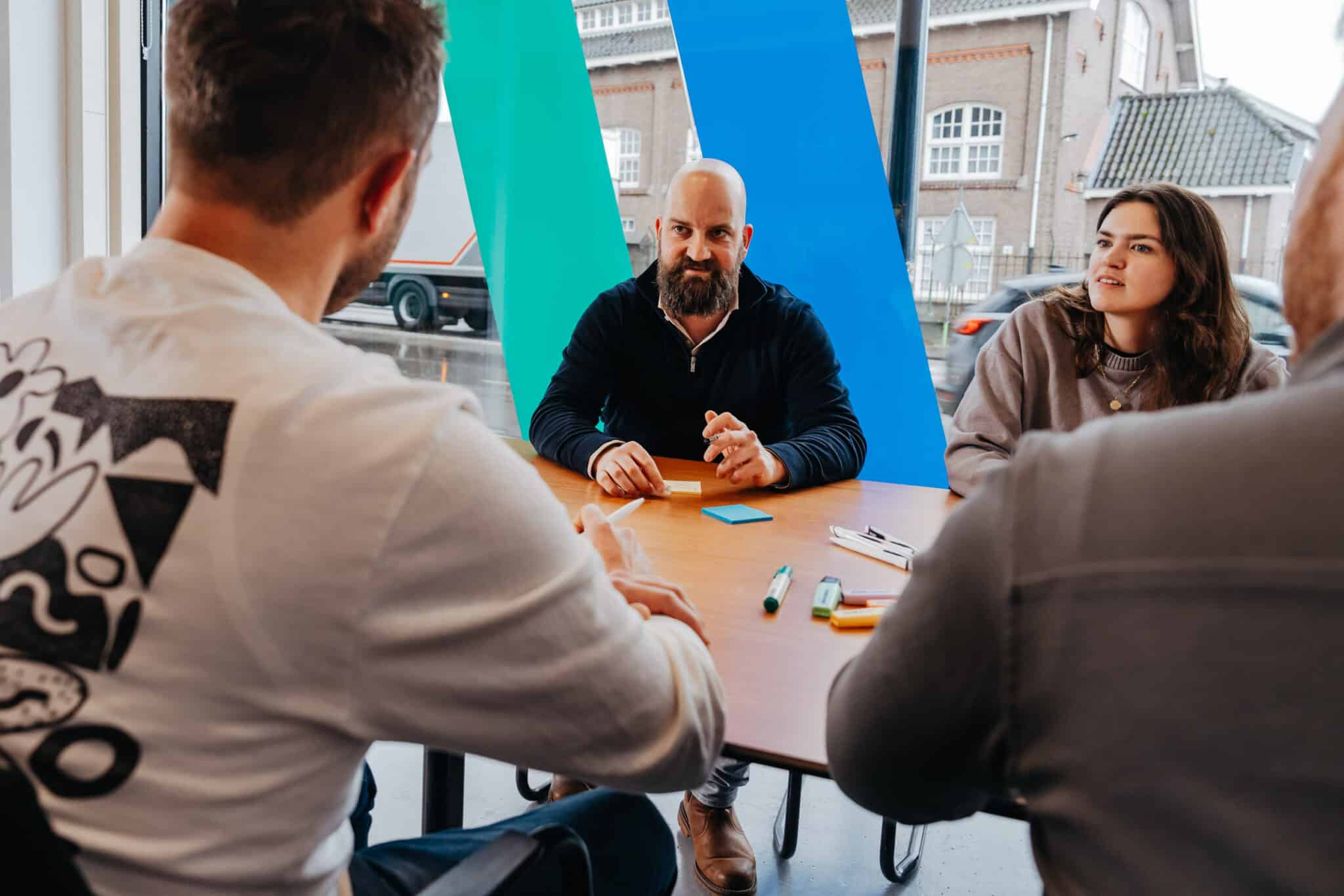Een multidisciplinair team bespreekt een websiteontwerp en technische planning aan een werktafel